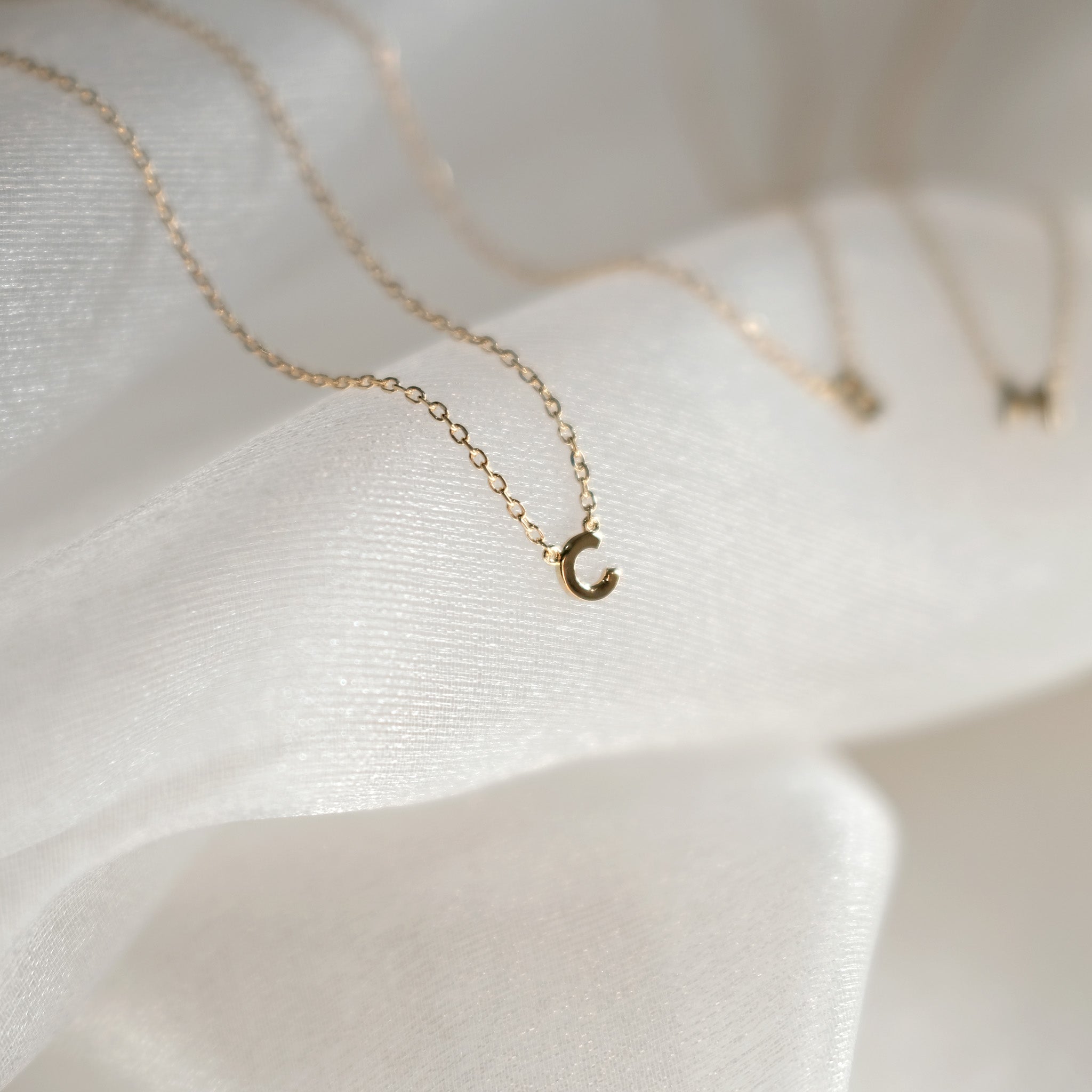 Gold necklace with a crescent moon pendant on a white fabric background