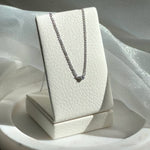 Video shoot of Silver necklace on a white jewelry display box against a soft fabric background