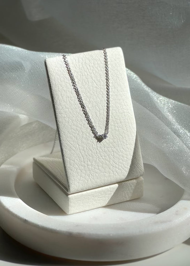 Video shoot of Silver necklace on a white jewelry display box against a soft fabric background