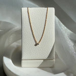Video shoot of Gold necklace on a white jewelry display box against a shimmery fabric background