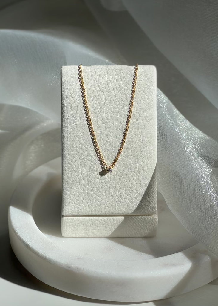 Video shoot of Gold necklace on a white jewelry display box against a shimmery fabric background