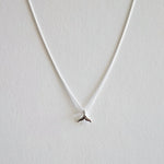 Silver necklace with a small pendant on a light gray background