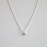 Silver necklace with a small pendant on a light gray background