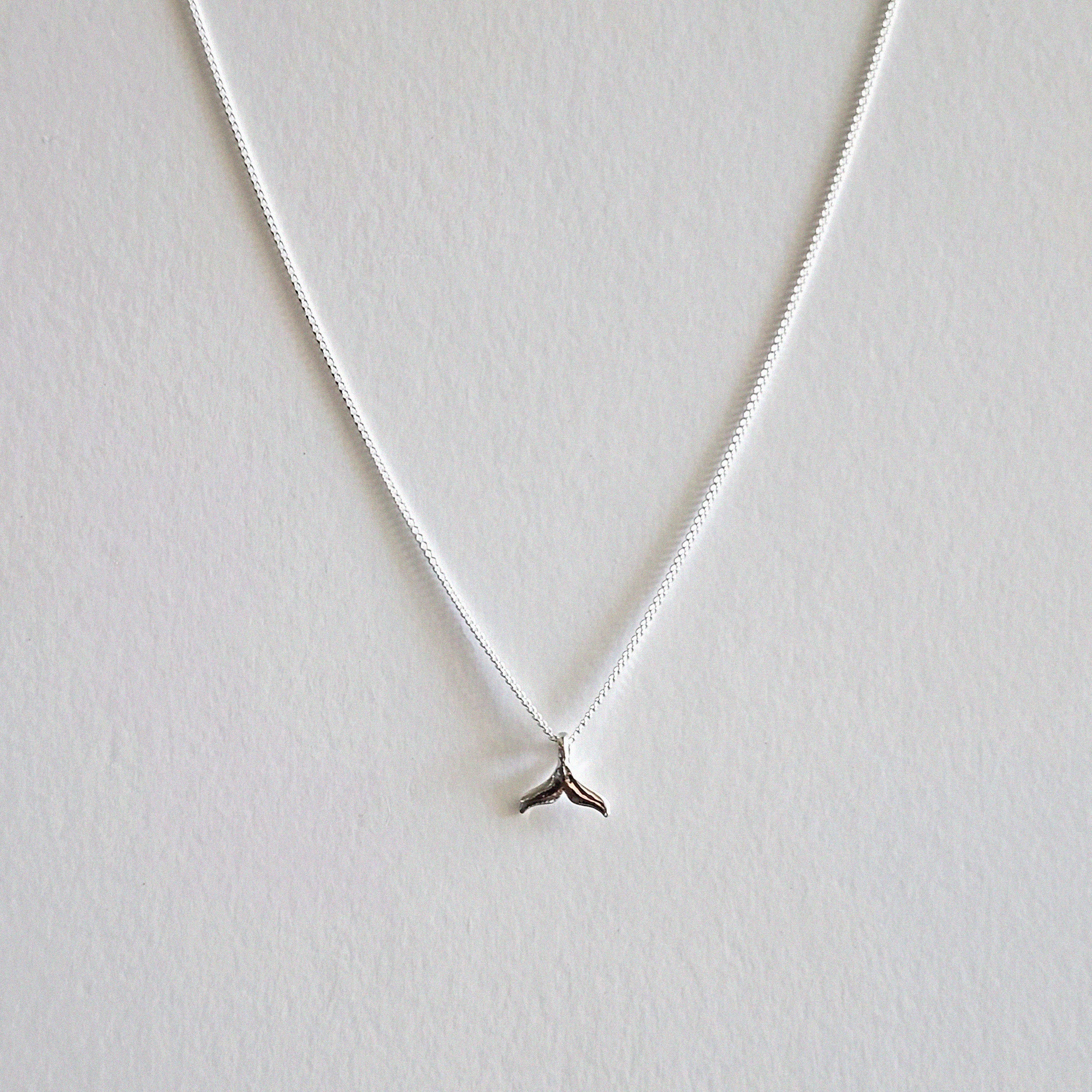 Silver necklace with a small pendant on a light gray background