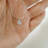 Silver necklace with a diamond pendant worn around the neck.