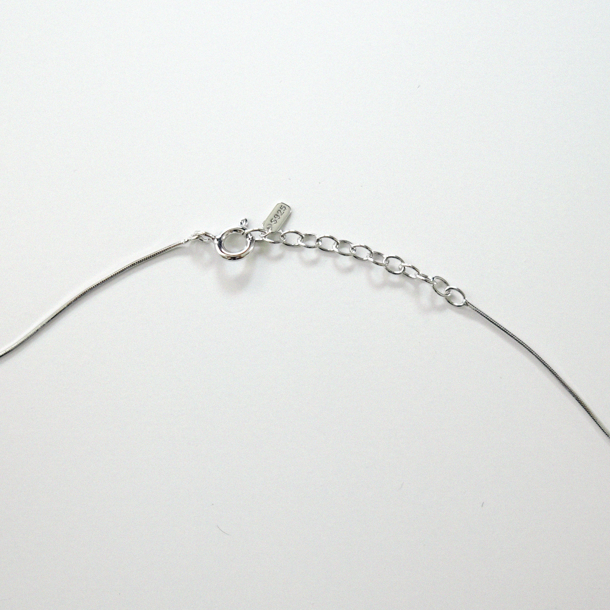 Silver necklace on a light gray background