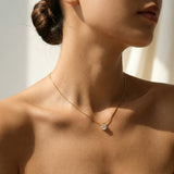 Close-up of a person wearing a delicate gold necklace with a small pendant.