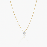 Gold necklace with a small round pendant on a white background