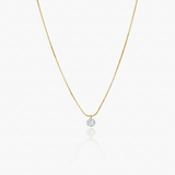 Gold necklace with a small round pendant on a white background
