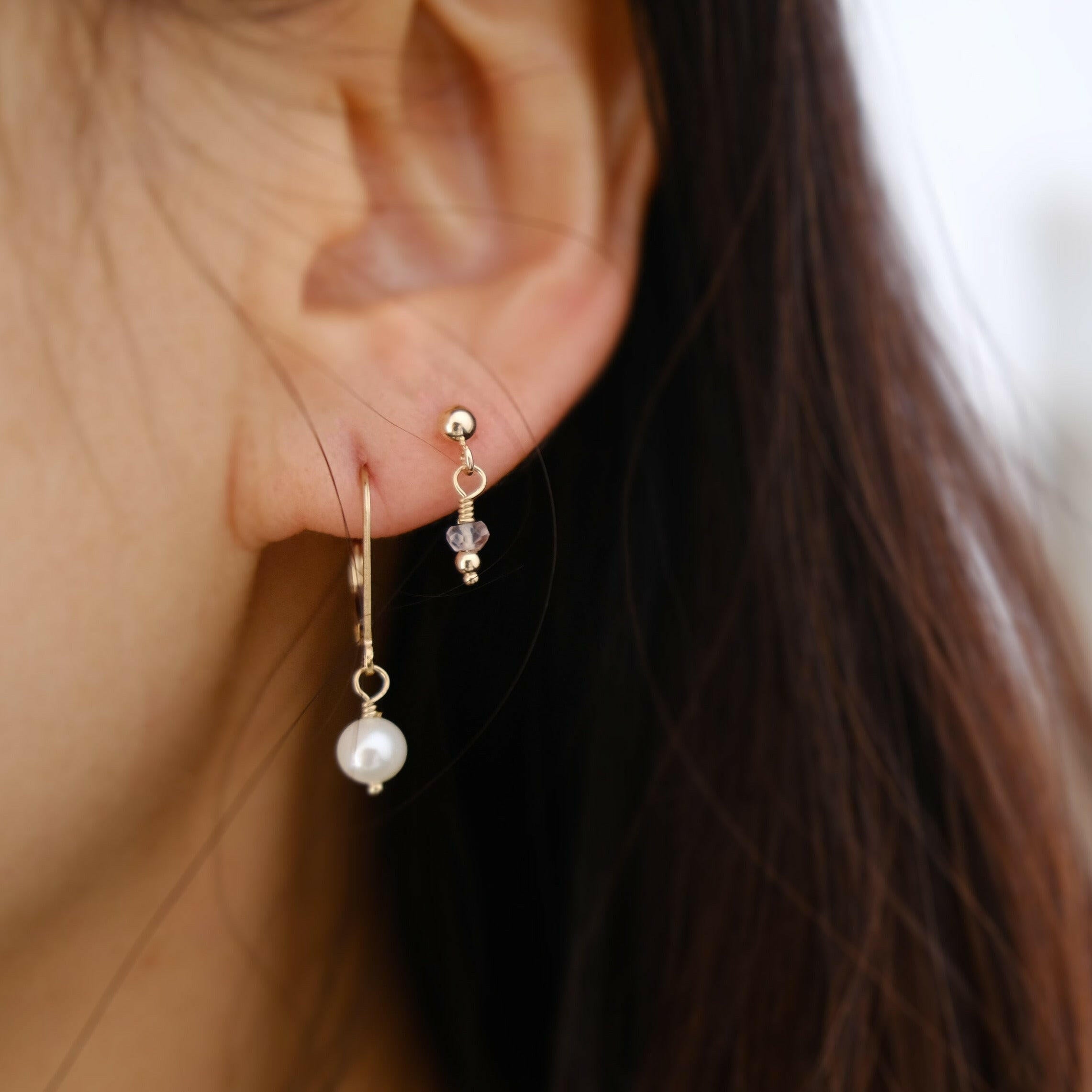 Model layering Piccola earrings with gold studs and Olivia Pearl Earrings.