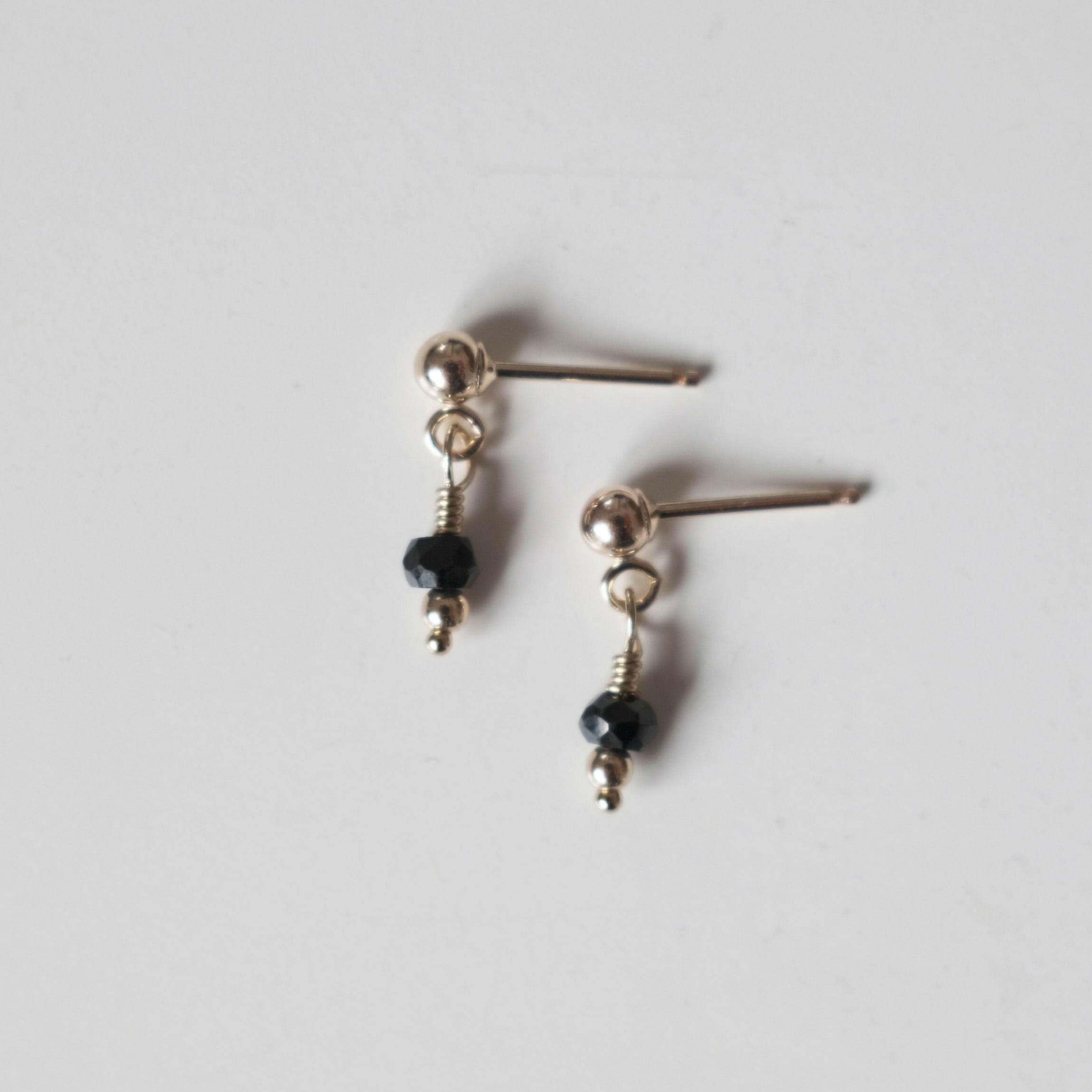 Petite gold drop earrings with small round black spinel gemstones and gold posts