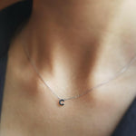 Necklace with a small letter 'T' pendant on a person's neck