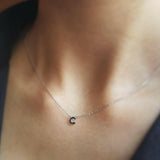 Necklace with a small letter 'T' pendant on a person's neck